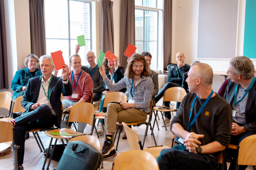Een aantal mensen houden rode en groene stemkaartjes in de lucht tijdens de debat sessie.